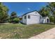 A bright home with black trim, green grass, and a matching detached garage at 1900 Kingston St, Aurora, CO 80010
