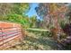 A grassy backyard space with mature trees viewed through a red gate offers plenty of possibilities at 7735 Westview Dr, Lakewood, CO 80214