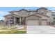 Beautiful home exterior with a three car garage, stone accents, and inviting covered front porch at 6614 S Vandriver Way, Aurora, CO 80016