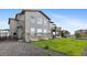 Back exterior of home with well-maintained lawn, stone accents, large windows, and small balcony at 6614 S Vandriver Way, Aurora, CO 80016
