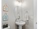 Powder room with neutral walls, accent art, decorative mirror, pedestal sink and white towel at 6614 S Vandriver Way, Aurora, CO 80016