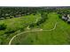 Aerial view of a green space with walking paths winding through lush greenery and scattered homes at 2011 Sundrop Trl, Highlands Ranch, CO 80126