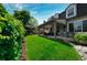 Lush backyard featuring a covered patio and seating area with a well-manicured lawn at 2011 Sundrop Trl, Highlands Ranch, CO 80126