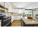 Bright kitchen featuring white cabinets, a gray countertop island, and stainless steel appliances at 2011 Sundrop Trl, Highlands Ranch, CO 80126