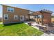 Landscaped backyard features a well-manicured lawn and a charming pergola-covered patio with stone accents at 261 Mesa Ave, Lochbuie, CO 80603