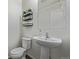 Compact powder room features a pedestal sink, a toilet, and decorative wall shelving for storage at 261 Mesa Ave, Lochbuie, CO 80603