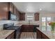 Open kitchen features dark cabinets, stainless steel appliances, granite countertops, and a view of the yard at 261 Mesa Ave, Lochbuie, CO 80603