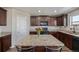 Kitchen featuring dark wood cabinetry, granite countertops, a kitchen island, and stainless steel appliances at 261 Mesa Ave, Lochbuie, CO 80603