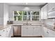 Well-lit kitchen with stainless steel dishwasher, white cabinetry, granite countertops and a window overlooking green scenery at 10345 Lions Heart, Lone Tree, CO 80124