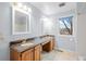 Bathroom featuring dual sinks with granite countertops, wooden cabinets, and bright vanity lighting at 16273 E Prentice Pl, Centennial, CO 80015