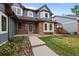 Inviting gray home featuring a brick facade, well-manicured lawn, and a walkway to the front door at 16273 E Prentice Pl, Centennial, CO 80015