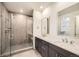 Modern bathroom with a glass-enclosed shower, dual vanity sinks, and neutral toned tile at 2924 S Poppy St, Morrison, CO 80465