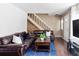 Comfortable living room with a large leather sofa, staircase, and a bright blue rug at 3820 S Fraser St, Aurora, CO 80014
