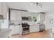 Bright kitchen features white cabinets, stainless appliances, subway tile backsplash, and wood floors at 4142 Chase St, Denver, CO 80212