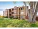Three-story tan apartment building with red trim surrounded by bushes and green lawn at 8770 Corona St # 101, Denver, CO 80229