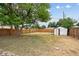 Fenced backyard with mature tree providing shade, and a small shed for storage at 1301 Kenton St, Aurora, CO 80010