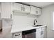 Kitchen features stainless steel dishwasher, white cabinets and countertops, and stylish black hardware at 1301 Kenton St, Aurora, CO 80010