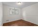Sunny bedroom with wood floor, white walls, and a window overlooking a wooded area at 3117 Victor St, Aurora, CO 80011
