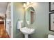 This powder bathroom features a pedestal sink, oval mirror, and neutral wall color at 1519 Stonehill Ct, Castle Rock, CO 80104