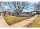 Exterior view of the property showcasing manicured lawn, mature trees, and brick-lined sidewalk at 5865 E Ithaca Pl, Denver, CO 80237