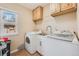 Functional laundry room with wooden cabinets, a utility sink, and modern washer and dryer units at 430 Osceola St, Denver, CO 80204