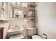 Bathroom featuring a sleek sink, silver shelving, toilet, and white walls to create a clean and modern design at 6940 W 63Rd Ave, Arvada, CO 80003