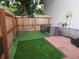 Fenced backyard with artificial grass lawn, bordered by a brick patio and garden tools at 3550 S Harlan St # 313, Denver, CO 80235