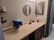Bathroom sink area featuring wood cabinets and a countertop with decor and round mirror at 3550 S Harlan St # 313, Denver, CO 80235