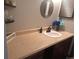Bathroom vanity featuring wood cabinets, tan countertop, decorative mirror, and black faucet at 3550 S Harlan St # 313, Denver, CO 80235