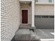 Inviting front entrance with a striking red door, accented by a white brick facade and a two-car garage at 547 Homestead Ave, Brighton, CO 80601
