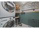 Functional laundry area with stacked washer and dryer, plus storage shelves and decor at 8699 Garrison Ct, Arvada, CO 80005