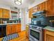 This kitchen features wood cabinets, stainless steel appliances, and a black and white rug at 1528 Holly St, Denver, CO 80220