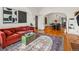 Open-concept living area showcasing hardwood floors, a plush sofa, decorative rug, and seamless flow into the dining room at 1528 Holly St, Denver, CO 80220