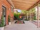 Covered patio area with outdoor seating, privacy landscaping, and access to a brick walkway at 1528 Holly St, Denver, CO 80220
