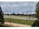 Expansive green backyard with a white fence line and views of snow-capped mountains at 12984 Crowfoot Springs Rd, Larkspur, CO 80118