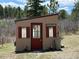 Charming garden shed with a red door, red shutters, and a 