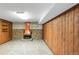 Spacious basement with unique stone flooring, wood-paneled walls, and brick fireplace at 5099 S Linden Dr, Englewood, CO 80110
