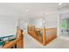 Bright upstairs hallway featuring hardwood railing and neutral carpet at 6808 Silverleaf Ave, Firestone, CO 80504