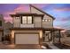 Charming two-story home at twilight featuring a front-facing garage, a welcoming porch, and modern architectural details at 10052 Zeno St, Commerce City, CO 80022