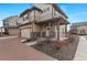 Inviting two-story home with a covered porch, stone accents, a two-car garage, and a well-maintained lawn at 10052 Zeno St, Commerce City, CO 80022