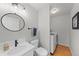 Well-lit bathroom featuring a modern vanity, round mirror, toilet, and a convenient in-unit washer and dryer at 9676 Whitecliff Pl, Highlands Ranch, CO 80129