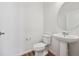 Modern powder room with pedestal sink, toilet, and wood-look floors at 6870 Merseyside Ln, Castle Pines, CO 80108