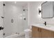 Modern bathroom features white tile shower with glass door and wood vanity with black hardware at 1459 W 42Nd Ave, Denver, CO 80211