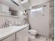 Bathroom featuring gray tiles, shower, toilet, white vanity, mirror, and window at 2560 Westchester Dr, Denver, CO 80221