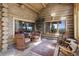 Cozy sunroom with log walls, stone floors, comfortable chairs, and bright, scenic views at 51 West Ranch Trl, Morrison, CO 80465