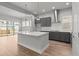 Open kitchen design with large island, gray cabinets, stainless hood, and wood flooring adjacent to living area at 21204 E 63Rd Dr, Aurora, CO 80019