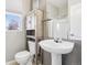 Bathroom featuring a pedestal sink, a toilet with a storage cabinet, and a window at 19677 E Vassar Dr, Aurora, CO 80013