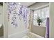 Well-lit bathroom features a shower with a floral curtain and decorative accents by the window at 19677 E Vassar Dr, Aurora, CO 80013