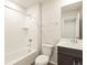 Full bathroom with white tiled shower and bath, matching toilet and dark wood vanity at 6581 N Malaya St, Aurora, CO 80019