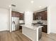 Modern kitchen with stainless steel appliances, a granite island, dark wood cabinets, and wood floors at 6581 N Malaya St, Aurora, CO 80019